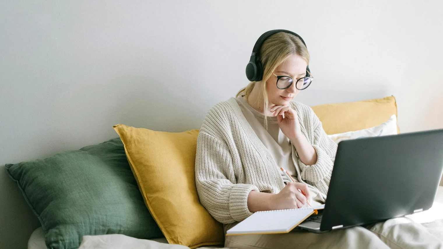Candidate writing career evidence notes beside a laptop while building an interview prep document