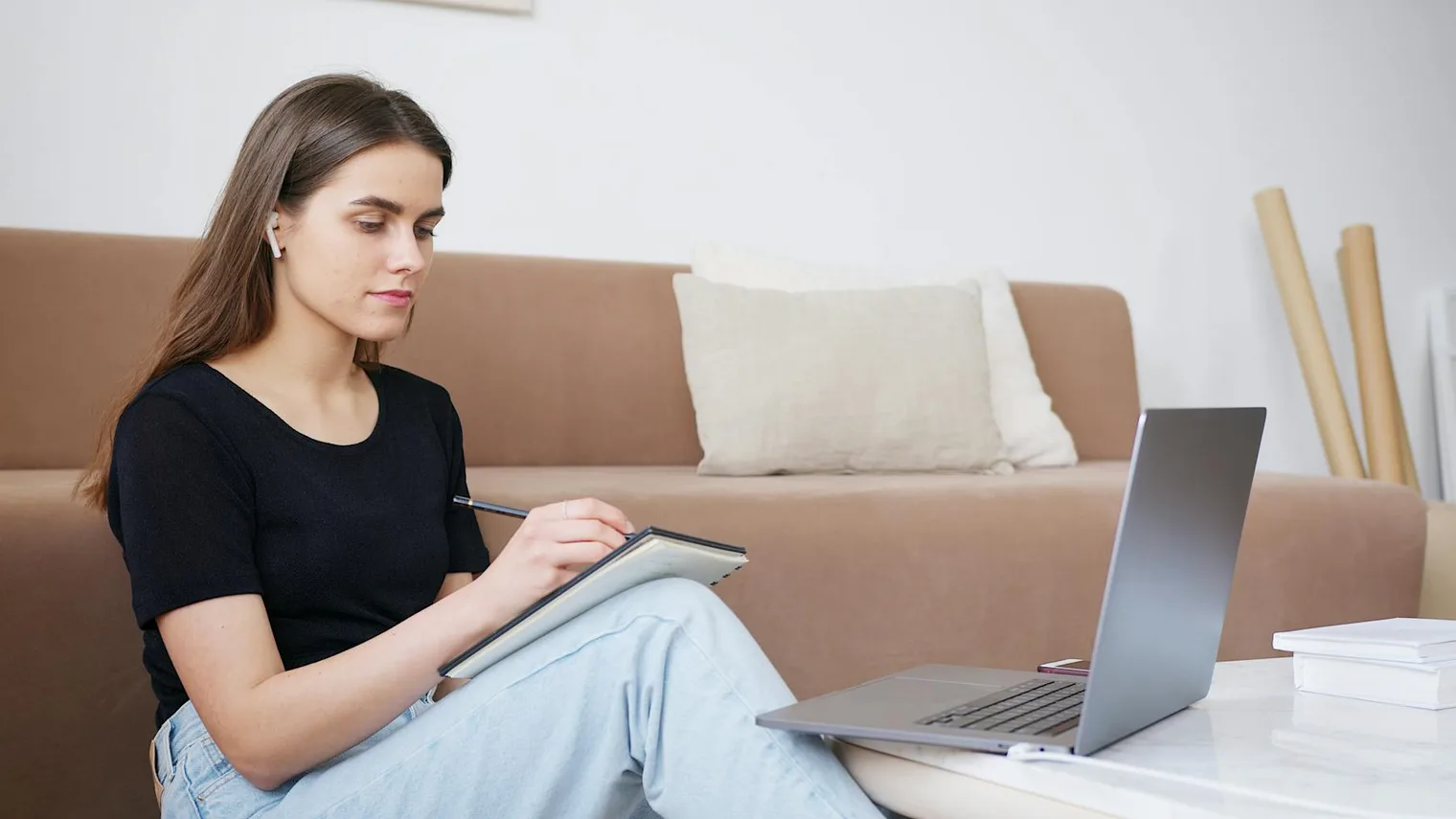 Candidate writing notes beside a laptop while practicing interview answers