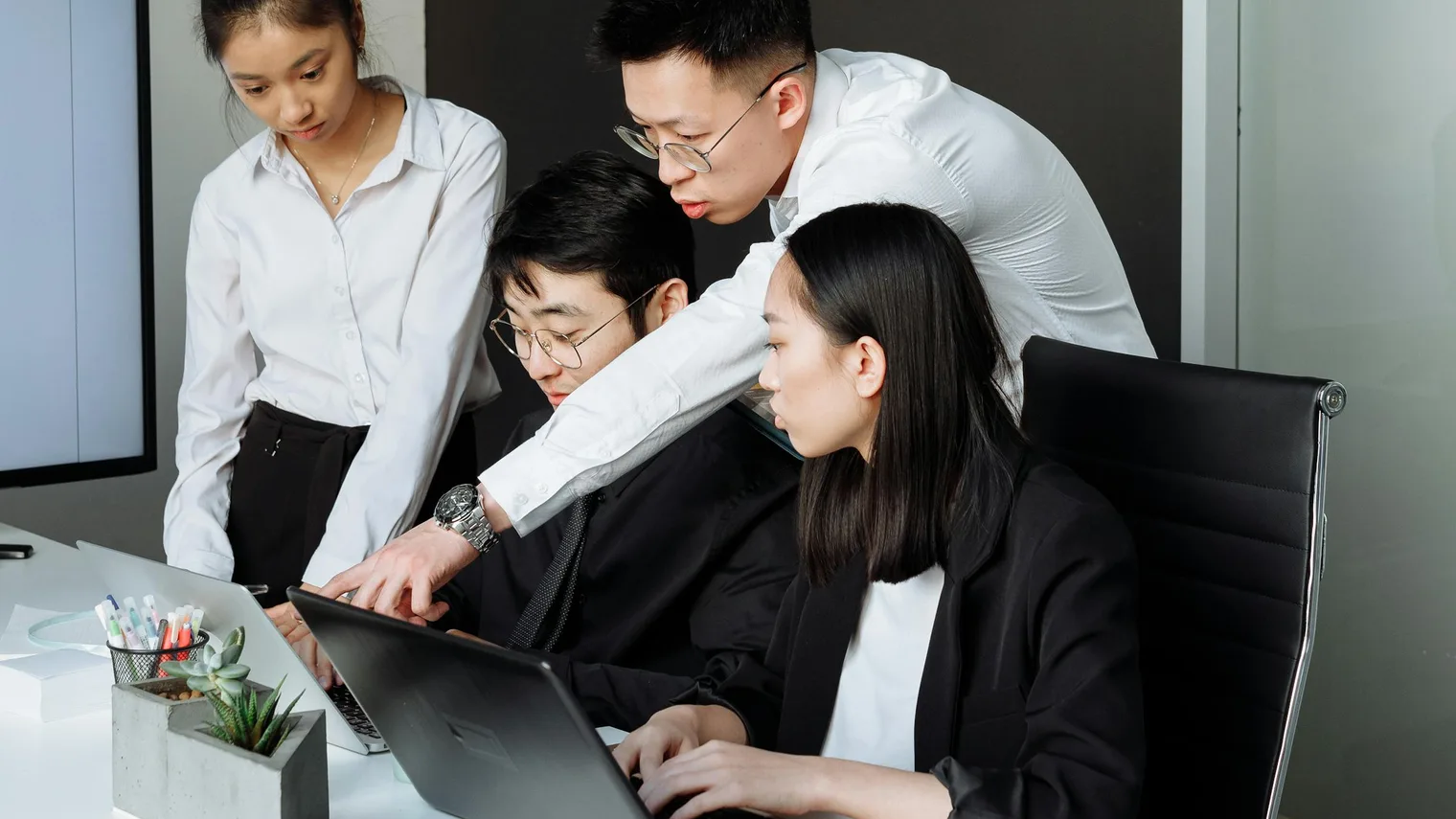 Panel interview preparation scene with several professionals reviewing role notes on a laptop