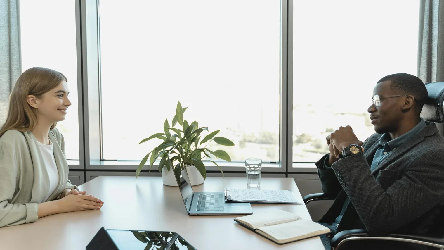 Candidate and interviewer having a positive post-interview conversation with notes and laptop on the table
