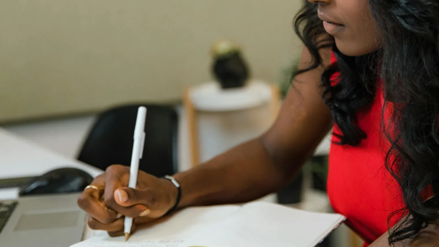 Candidate writing resume strength evidence in a notebook beside work documents