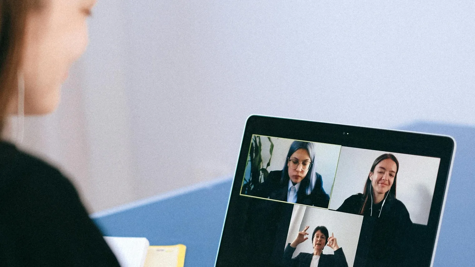 Candidate taking notes beside a laptop while checking virtual interview camera setup