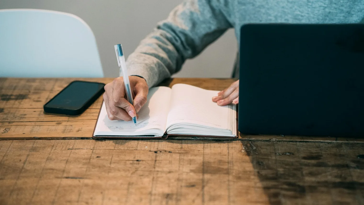 Candidate writing interview story cues in a notebook beside a laptop