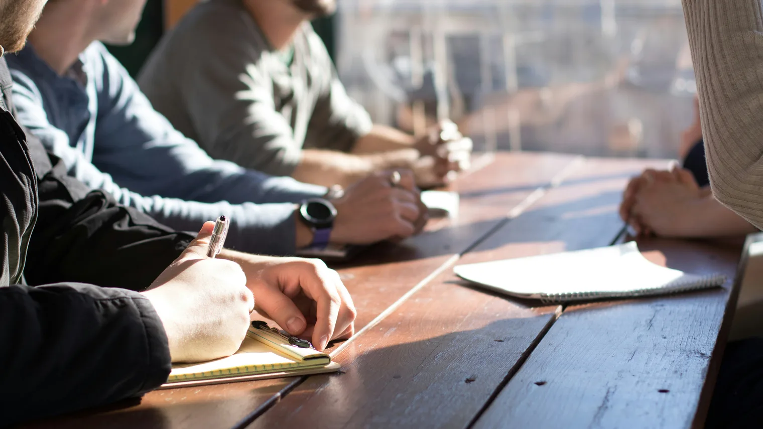 People reviewing notes around a table after recorded interview practice