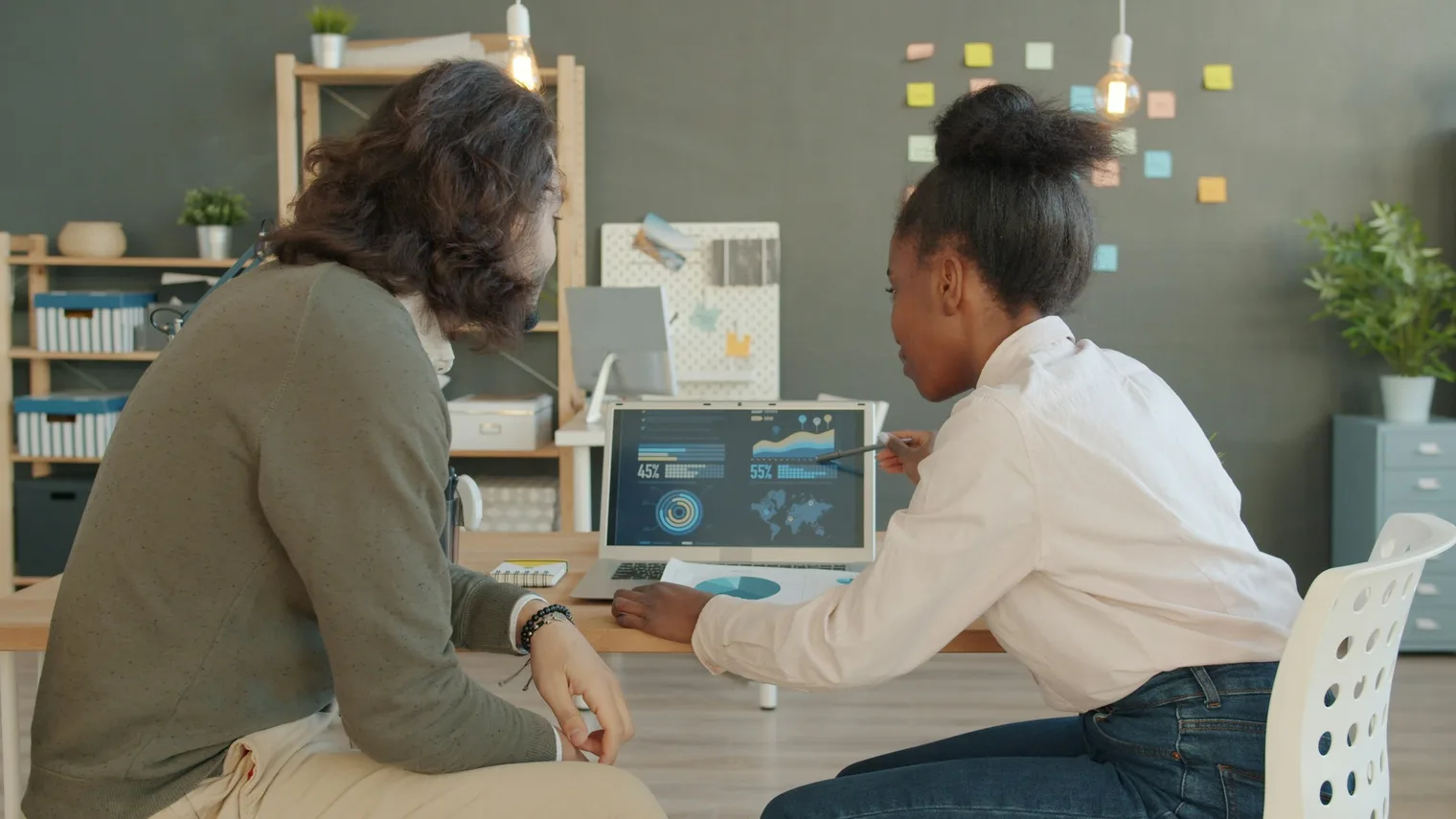 Two people reviewing search analytics on a laptop while preparing SEO interview questions